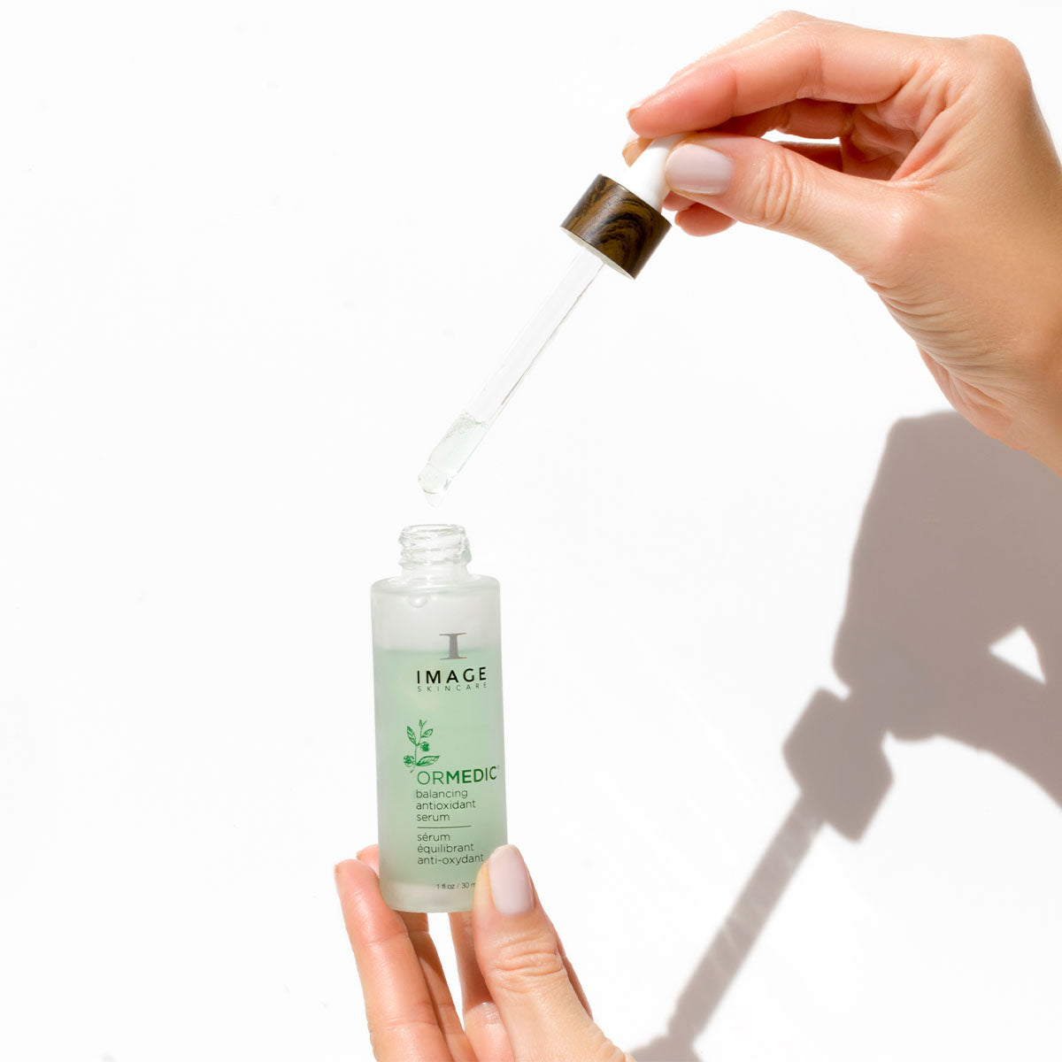 Woman holding an open bottle of ORMEDIC antioxidant serum.